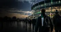 Supporters walking toward a stadium at dusk